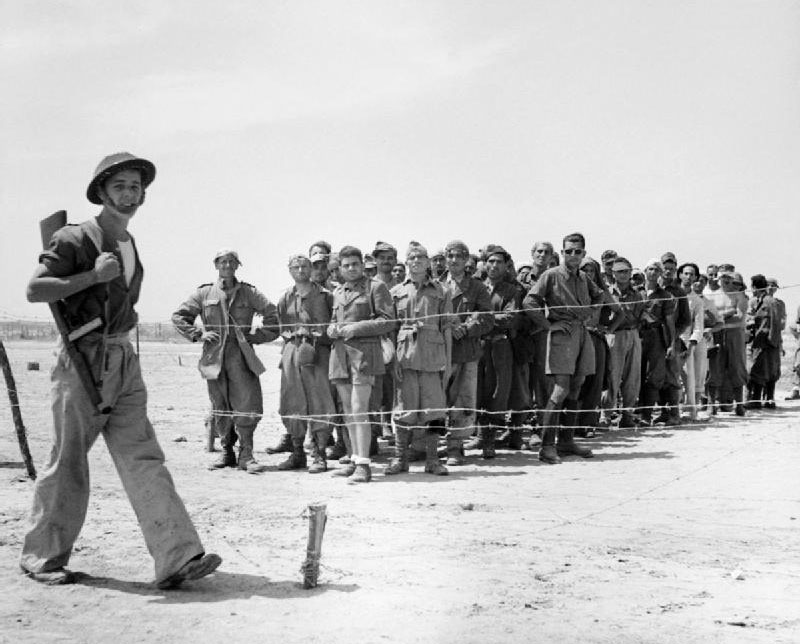 Британский солдат охраняет группу пленных итальянцев и немцев на Сицилии, 1943 г.